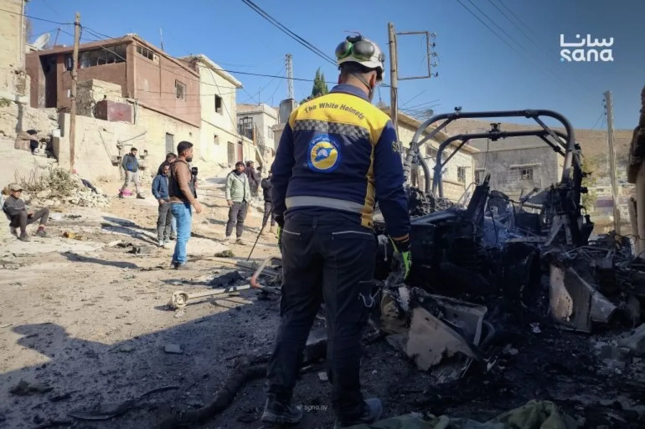 عناصر دفاع مدني سوري أمام مركبة دمرها الجيش الإسرائيلي أمس في بيت جن