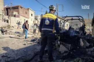 عناصر دفاع مدني سوري أمام مركبة دمرها الجيش الإسرائيلي أمس في بيت جن