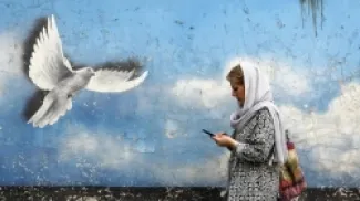 امرأة إيرانية تمرّ بجانب لوحة جدارية لطائر السلام في أحد شوارع وسط طهران