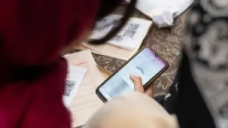 امرأة ترتدي حجاباً أحمر تنظر إلى هاتف يعمل عليه تطبيق الـVPNصدر الصورة،NurPhoto / Getty Images