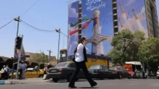 امرأة تمر أمام لافتة عملاقة تصور صواريخ إيرانية وسيفًا للإمام علي، الإمام الأول للشيعة، في ساحة فاناك في طهران في 10 يونيو/حزيران 2026. صدر الصورة،AFP via Getty Images