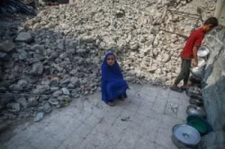 طفلة فلسطينية تجلس بجوار أنقاض مبانٍ مدمّرة، فيما يقف طفل آخر بالقرب منها في مخيم جباليا للاجئين شمالي قطاع غزة، فلسطين